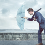 Plausch hinterm Schloss: Resilienz am Arbeitsplatz; Mann hält bei Regenwetter seinen Schirm gegen den Wind