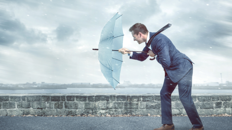Plausch hinterm Schloss: Resilienz am Arbeitsplatz; Mann hält bei Regenwetter seinen Schirm gegen den Wind